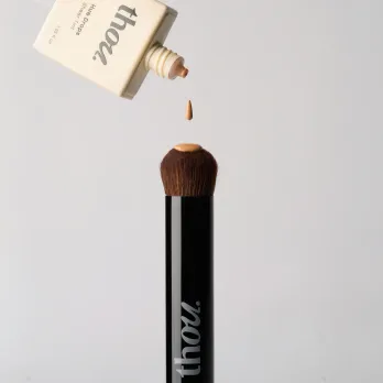 Skin tint from Thou Beauty's bottle pouring out on a brush