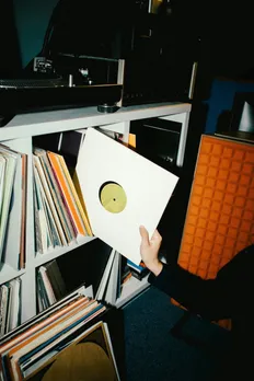 A person sifts though vinyl records at a store to show how nostalgia in India is coming back in music via vinyl records and analog revival India
