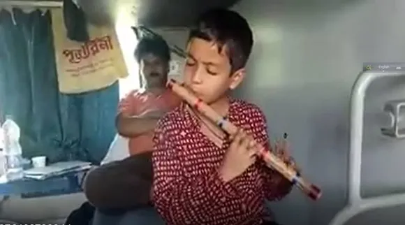 young boy playing flute on train feature pic