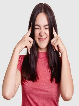 Desperate brunette woman keeps index fingers on temples, has terrible headache, tries to gather with thoughts, dressed in casual pink t shirt, isolated over white background. Negative feeling concept