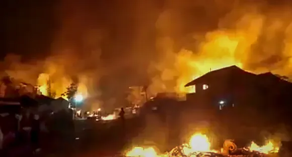 Flames rise from structures lit on fire after violence broke out between tribals and non-tribals