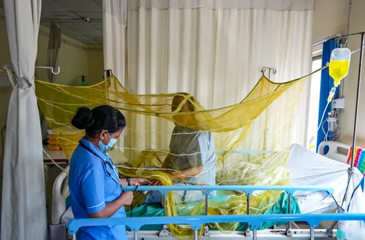  A hospital staffer attends a dengue patient under a mosquito net at a city hospital, in Kolkata