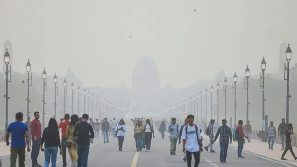 People walk on the Kartavya Path as smog shrouds Raisina hill, in New Delhi