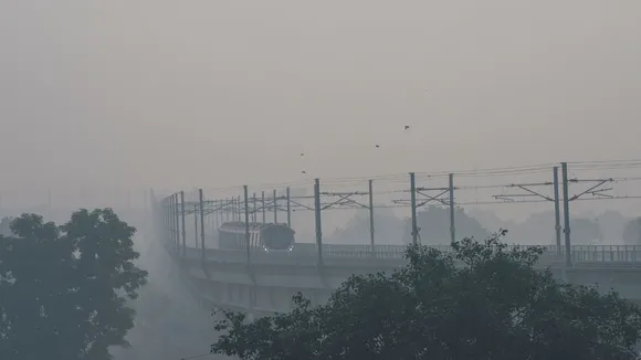 A metro train runs on its track amid smog, in New Delhi
