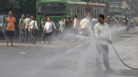 A worker sprinkles water to curb air pollution at Jahangirpuri, in New Delhi, Saturday, Oct. 26, 2024