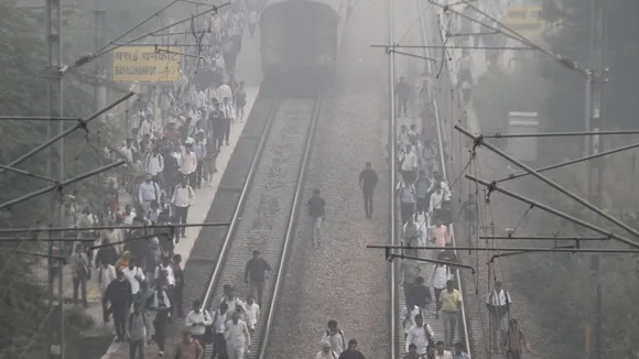 People walk on the railway tracks amid low visiblity due to smog in Gurugram
