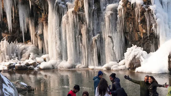 Tourists click photographs as they visit the frozen Drung waterfall, at Tangmarg in Baramulla district, North Kashmir