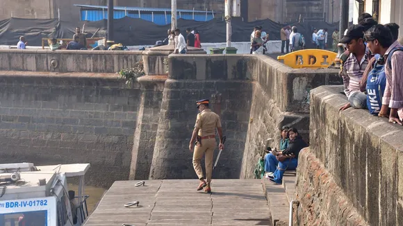 A police personnel keeps vigil at the coast as people look on following an incident where a ferry capsized off the Mumbai coast when a Navy craft crashed into it on Wednesday, in Mumbai, Thursday, Dec. 19, 2024.