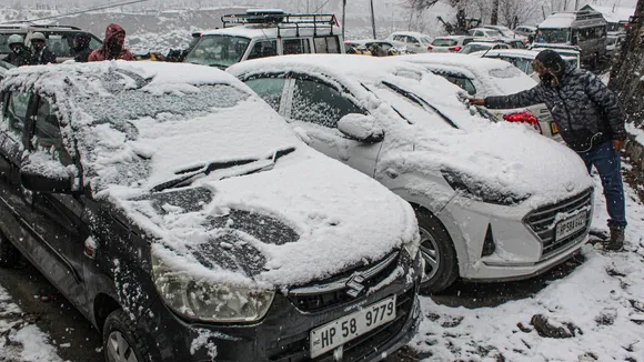 A man removes snow from vehicles after fresh snowfall, in Manali, Himachal Pradesh