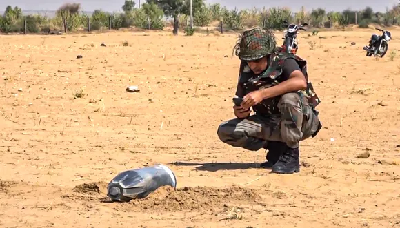 A security personnel inspects the debris of an unidentified projectile which landed amid the military conflict between India and Pakistan, in Jaisalmer.
