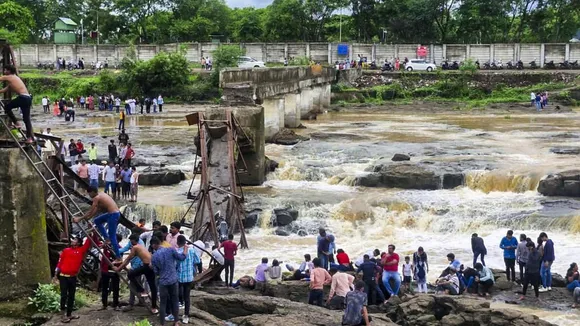 People stand near an iron bridge over the Indrayani river after it collapsed, in Pune district, Maharashtra, Sunday, June 15, 2025.