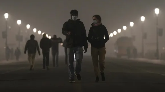 Pedestrians wear masks as a layer of smog engulfs the city amid deterioration in the capital's air quality, in New Delhi, Thursday, Dec. 18, 2025.