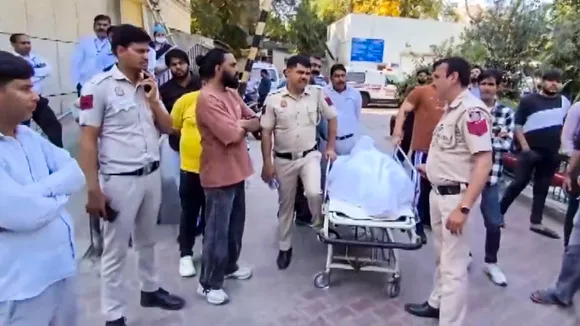 Police personnel and locals gather as a body is taken on a stretcher following the alleged stabbing of a youth in the Uttam Nagar area of southwest Delhi, in New Delhi, Thursday, March 5, 2026.