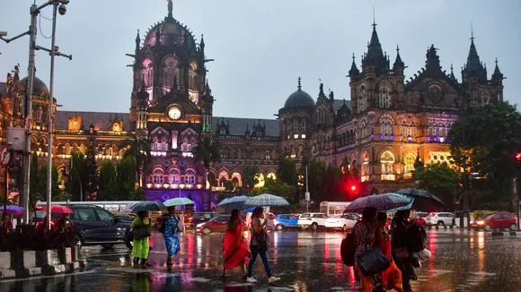 Pedestrians cross a road amid rain, in Mumbai