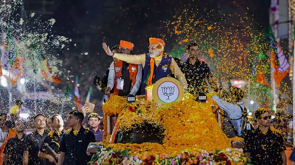 Prime Minister Narendra Modi waves at supporters during a roadshow ahead of the Madhya Pradesh Assembly elections, in Indore