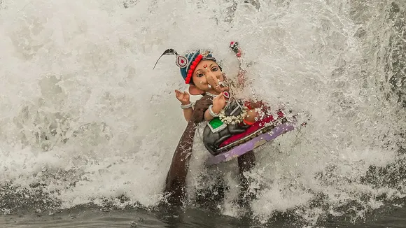 A volunteer carries an idol of the Hindu god Ganesha for immersion