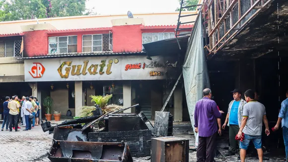 People stand at Gulati Restaurant where a fire broke out, in New Delhi, early Wednesday, July 17, 2024.