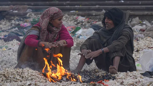 People warm themselves with a bonfire during a cold and foggy winter morning