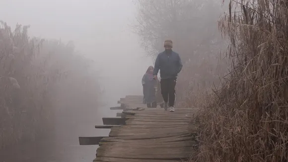  People crossing a wooden bridge amid dense fog, in Srinagar