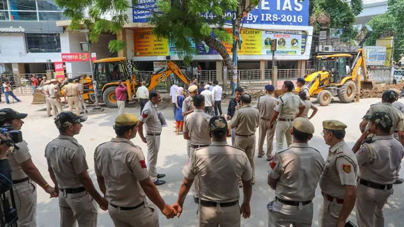 Police personnel guard as a bulldozer demolishes parts of the IAS coaching institute in Old Rajinder Nagar, where 3 students died due to drowning, in New Delhi, Monday, July 29, 2024.