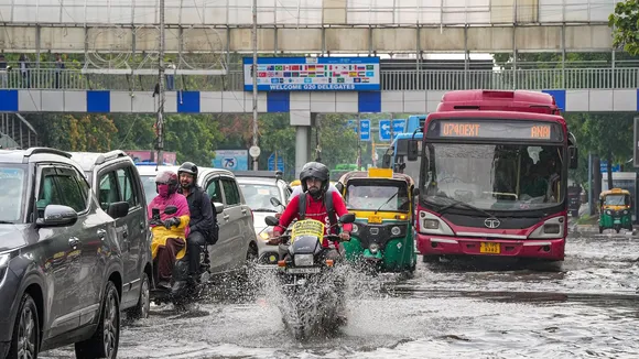 Commuters wade through a waterlogged road during rains, near ITO, in New Delhi, Tuesday, July 9, 2024.