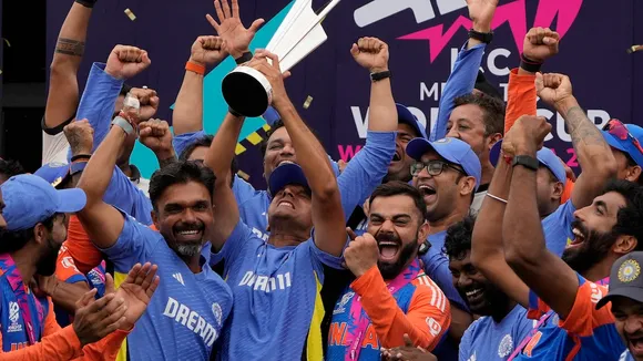 India's head coach Rahul Dravid, center left, and Virat Kohli, center right, celebrate with players and team support staff with the winners trophy after defeating South Africa in the ICC Men's T20 World Cup final cricket match at Kensington Oval in Bridgetown, Barbados, Saturday, June 29, 2024.