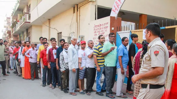 Voters stand in a queue at a polling station to cast their vote, during the sixth phase of Lok Sabha elections, in Gurugram, Saturday, May 25, 2024