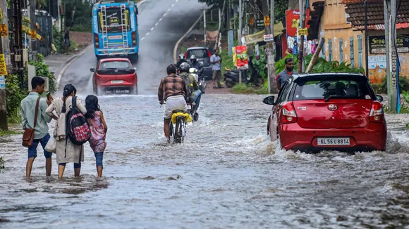Commuters make their way through a flooded road following rains, in Kozhikode, Tuesday, July 16, 2024.
