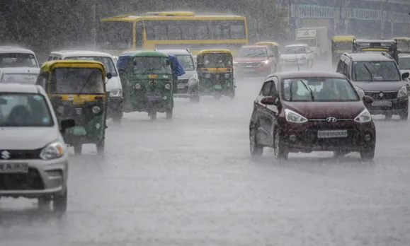 Vehicles ply on a road amid rainfall, in Gurugram