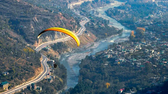 A paraglider flies from the paragliding site Peej, in Kullu district