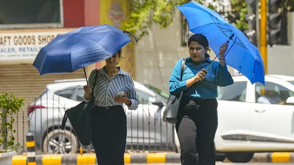 Women cover themselves under umbrellas during heatwave, in New Delhi, Saturday, June 14, 2024