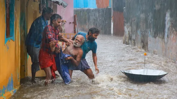 People rescue an elderly man from a flooded area during heavy rain, in Kanyakumari district