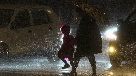 Pedestrians cross a road amid rainfall, in Mumbai, Wednesday, July 19