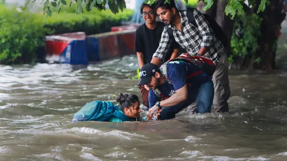 People help a pedestrian who fell on a flooded road after heavy monsoon rains, at ITO in New Delhi, Tuesday, Aug. 20, 2024