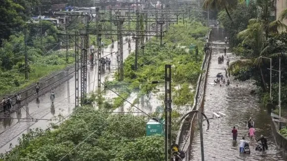 People make their way through a waterlogged street following rains, in Mumbai, Monday, July 8, 2024