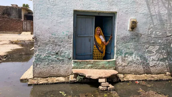 A woman peeps out of her window in a village in Hathras