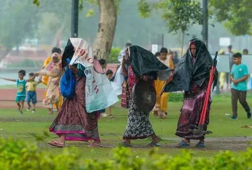 Women try to protect themselves amid, rains near India Gate, in New Delhi