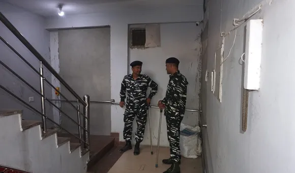 Security personnel guard during raids by Delhi Police's Special Cell on the premises of NewsClick at Sainik Farm, in New Delhi
