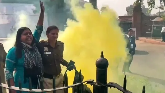 Police personnel detain a woman protesting outside the Parliament building carrying a can emitting a yellowish smoke during the Winter session, in New Delhi, Wednesday, Dec. 13, 2023.