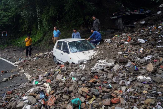 People try to get a vehicle out of debris after it got buried after heavy rainfall, in Shimla