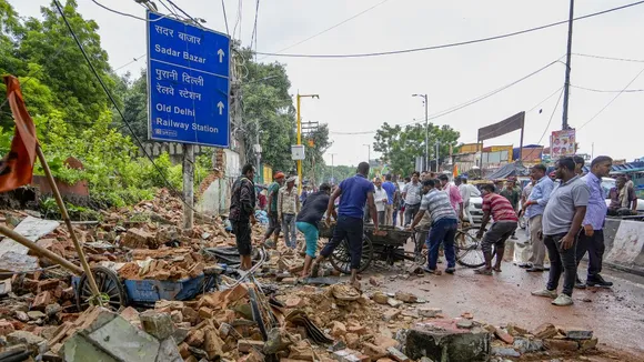 People look on as an excavator is being used to remove the debris after a wall of a 'dargah' collapsed at Nabi Karim area, in New Delhi, Friday, Sept. 13, 2024. 