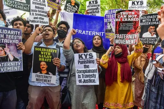 People hold placards and shout slogans during a protest against the arrest of social activist & journalist Teesta Setalvad