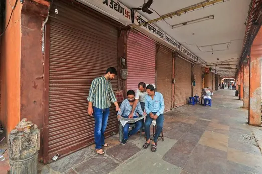 Locals read a newspaper at a deserted market during a bandh called by various Hindu organisations over the murder of tailor Kanhaiya Lal in Udaipur, in Jaipur