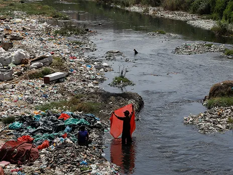 A man washes plastic sheets for recycling in polluted waters on World Environment Day in Karachi (File Photo/Reuters)