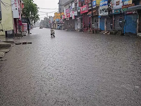 A man drags his cycle through waterlogged road following heavy rainfall, in Jhajjar (Photo/ANI)