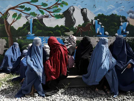 Afghan women wait to receive food packages distributed by a Saudi Arabian humanitarian aid group at a Kabul distribution center (File Photo/Reuters)