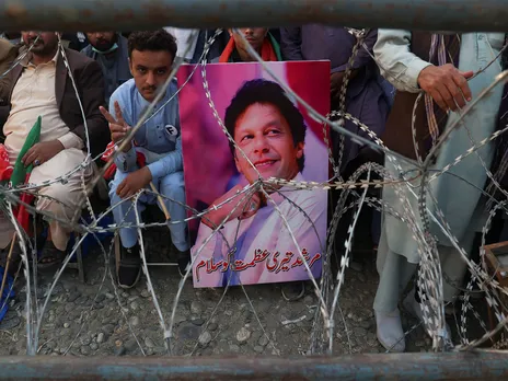 A supporter of jailed former Pakistani Prime Minister Imran Khan's party, the Pakistan Tehreek-e-Insaf holds his poster (Image/Reuters)