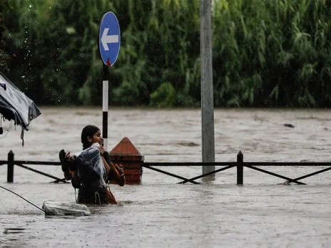 A woman wades through a flooded road along the overflowing Bagmati River carrying her belongings after heavy rains in Kathmandu, Nepal (File Photo/Reuters)