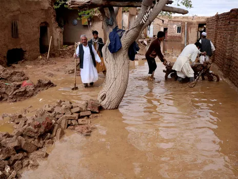 Residents clear debris and wade through floodwater after heavy rains and flash floods hit parts of Afghanistan. (File Photo/Reuters)
