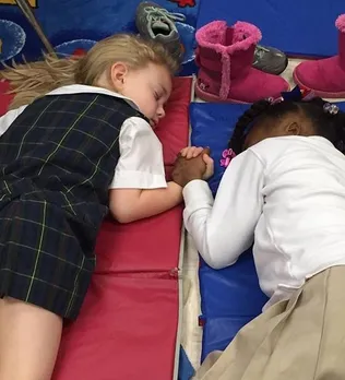 Photo of two little girls lying hand-in-hand during naptime goes viral